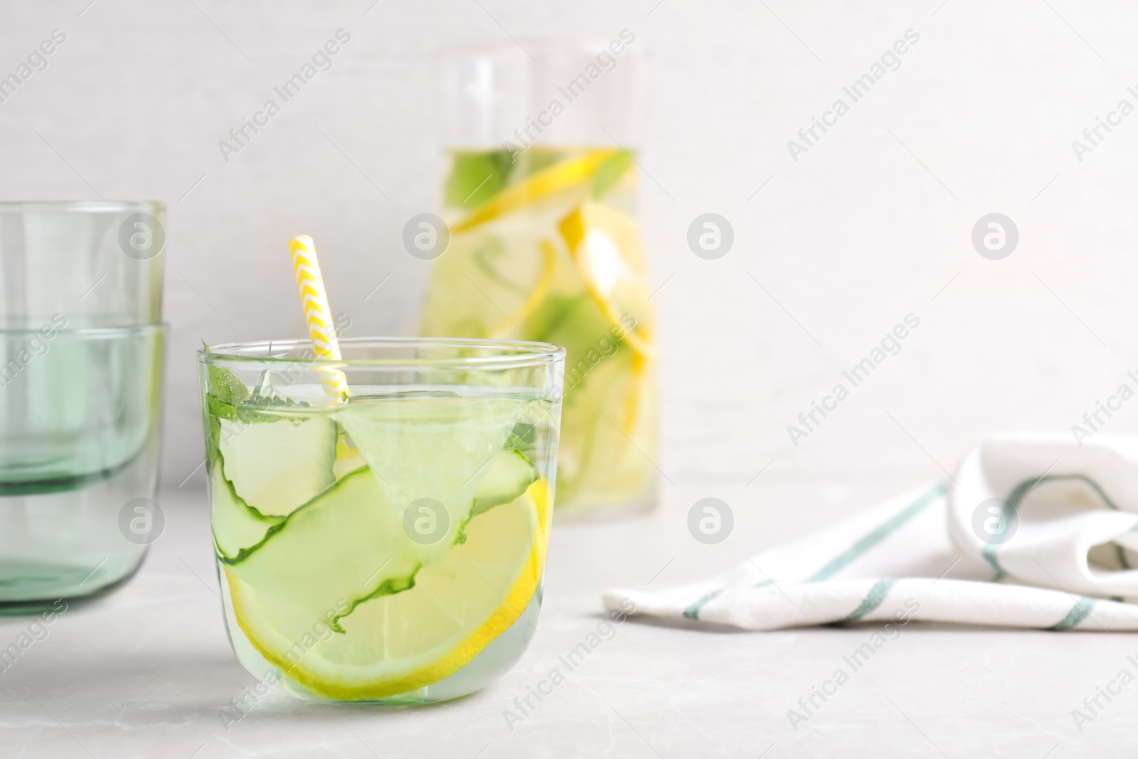 Photo of Refreshing water with cucumber, lemon and mint on white table