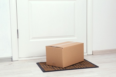 Photo of Cardboard box on floor near apartment entrance. Mockup for design