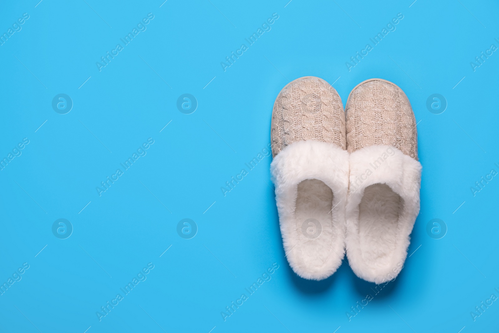 Photo of Pair of beautiful soft slippers on light blue background, top view. Space for text