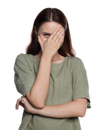 Embarrassed young woman covering face with hand on white background