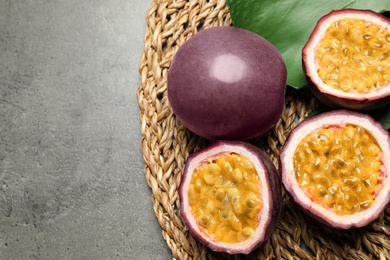 Photo of Passion fruits (maracuyas) and green leaf on grey table, flat lay. Space for text