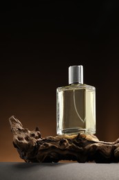 Photo of Luxury men`s perfume in bottle on grey table against brown background