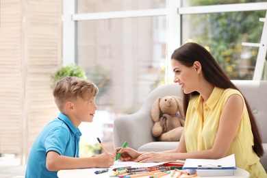 Photo of Young female psychologist working with little child in office