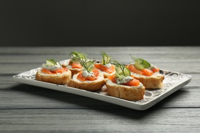 Photo of Tasty canapes with salmon, cucumber, cream cheese and dill on wooden table