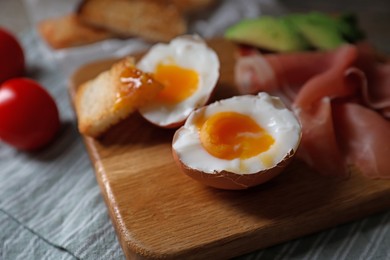 Photo of Delicious breakfast with soft boiled egg and tasty prosciutto on table, closeup