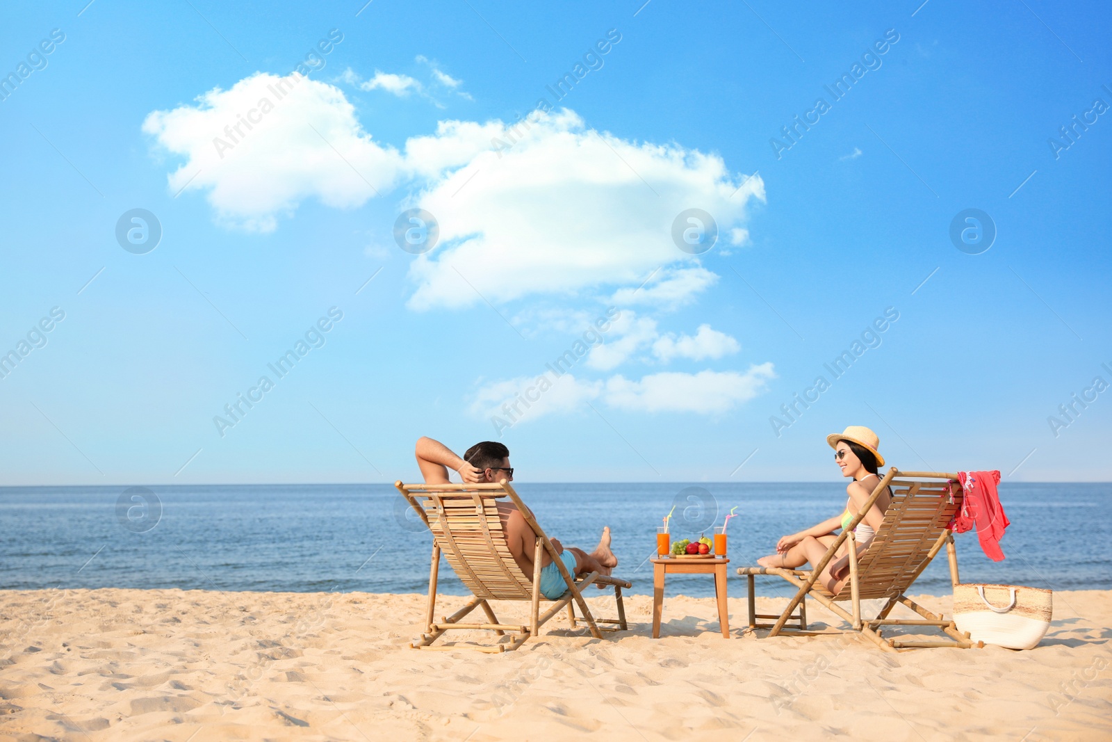 Photo of Couple resting on sunny beach at resort. Space for text