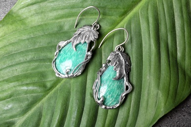 Photo of Beautiful pair of silver earrings with amazonite gemstones on green leaf, above view