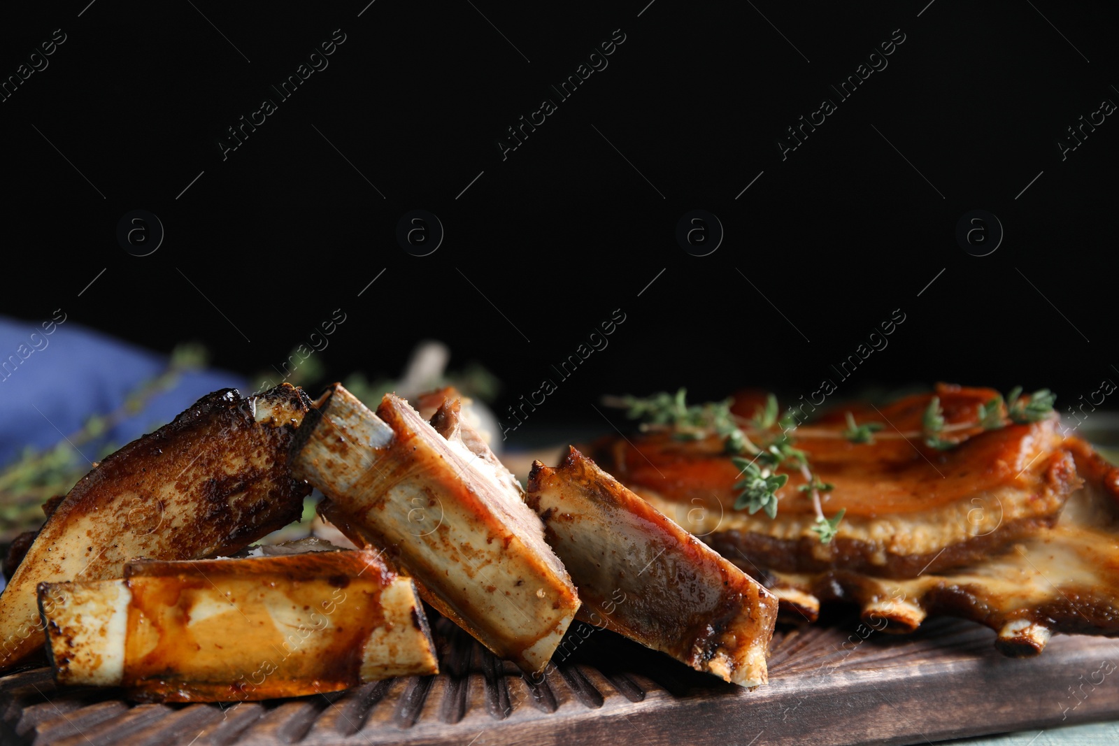 Photo of Delicious roasted ribs served on wooden board, closeup
