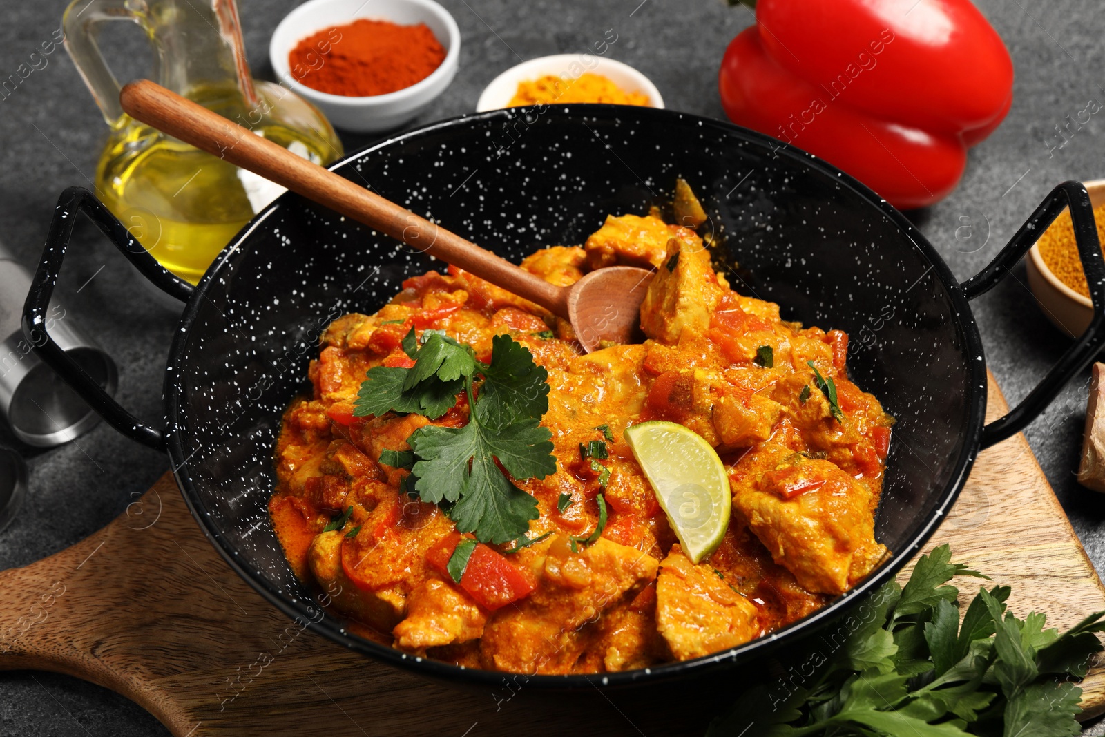 Photo of Delicious chicken curry and ingredients on grey table