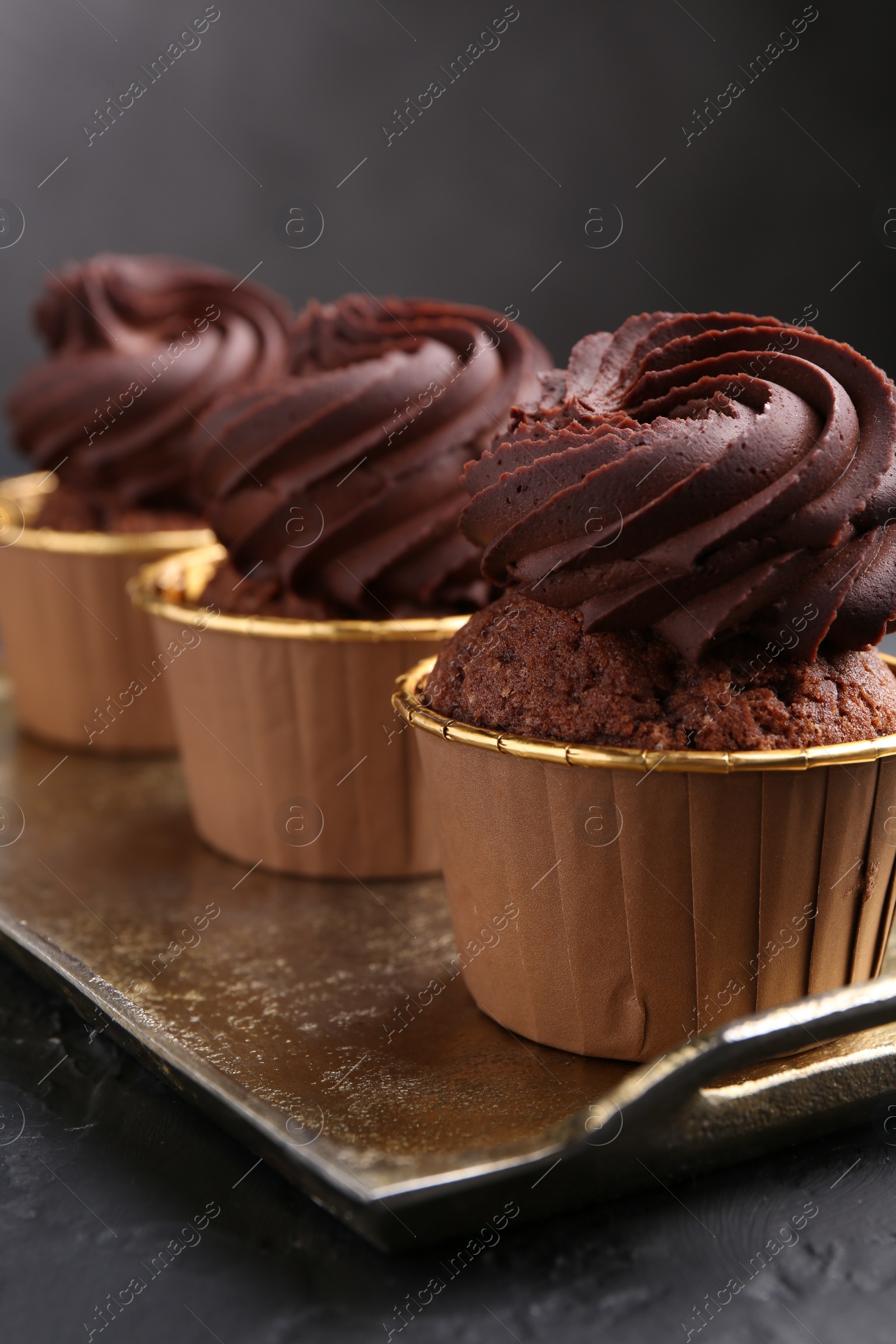 Photo of Delicious chocolate cupcakes on black textured table, closeup