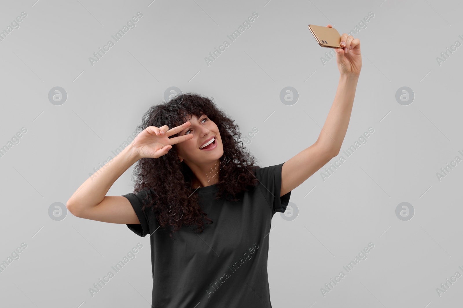 Photo of Beautiful young woman taking selfie on light grey background