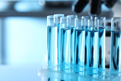 Test tubes with light blue liquid in laboratory, closeup. Space for text