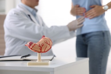 Photo of Gastroenterologist examining patient in clinic, focus on human stomach model