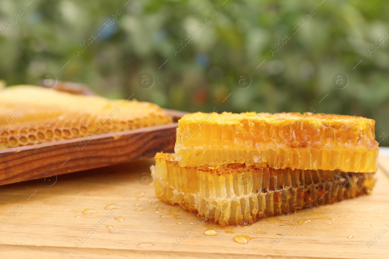 Photo of Fresh delicious honeycombs and hive frame on wooden table