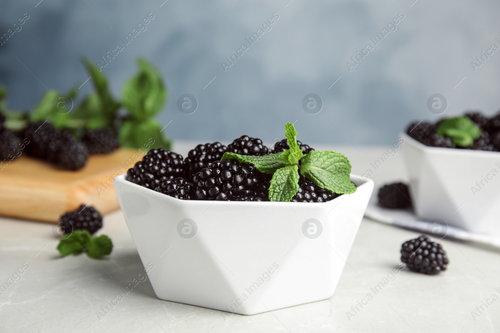 Photo of Bowl of tasty blackberries on grey marble table