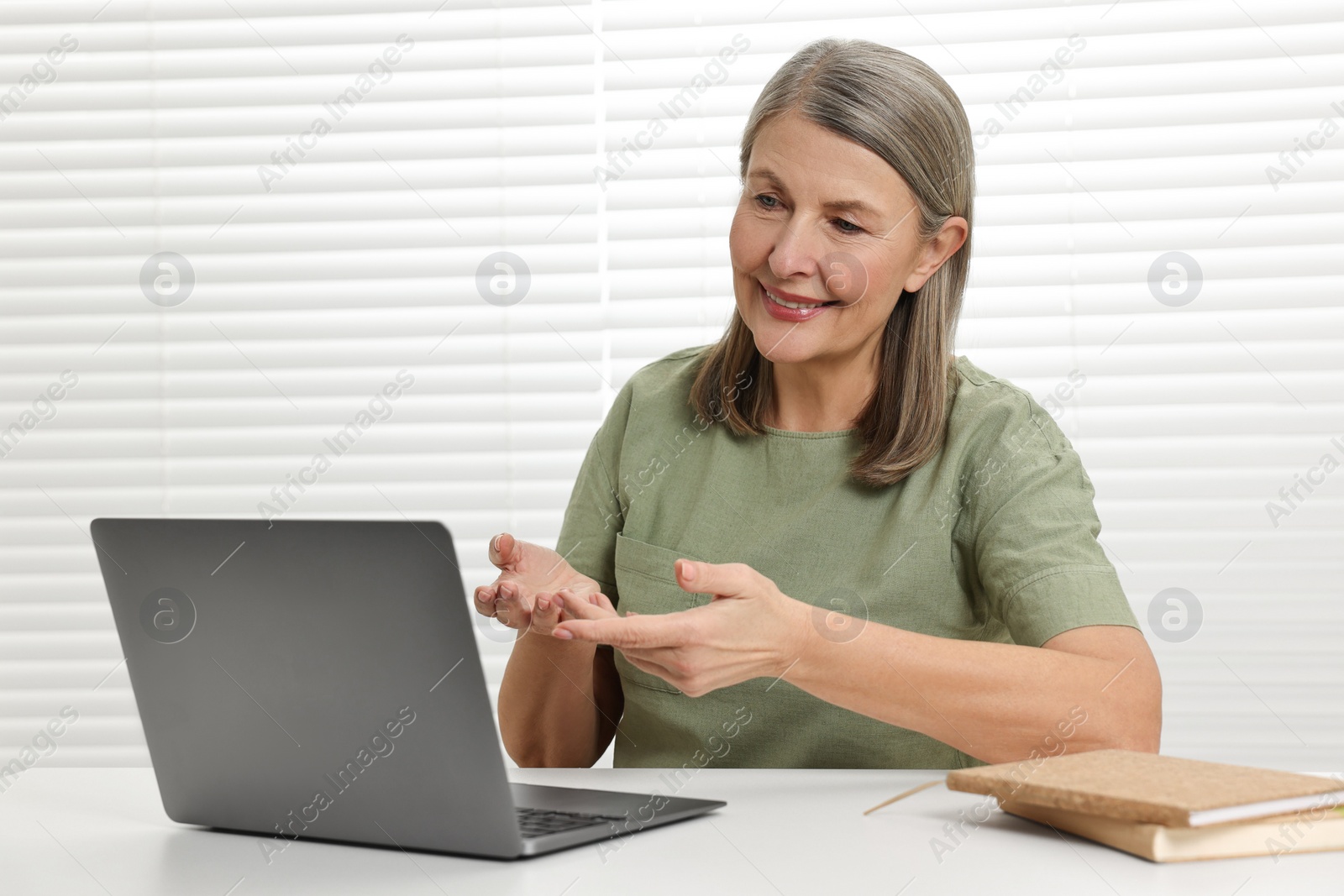 Photo of Happy woman having video chat via laptop at table indoors