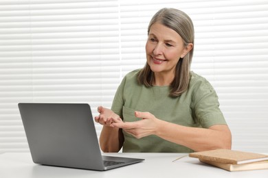 Happy woman having video chat via laptop at table indoors