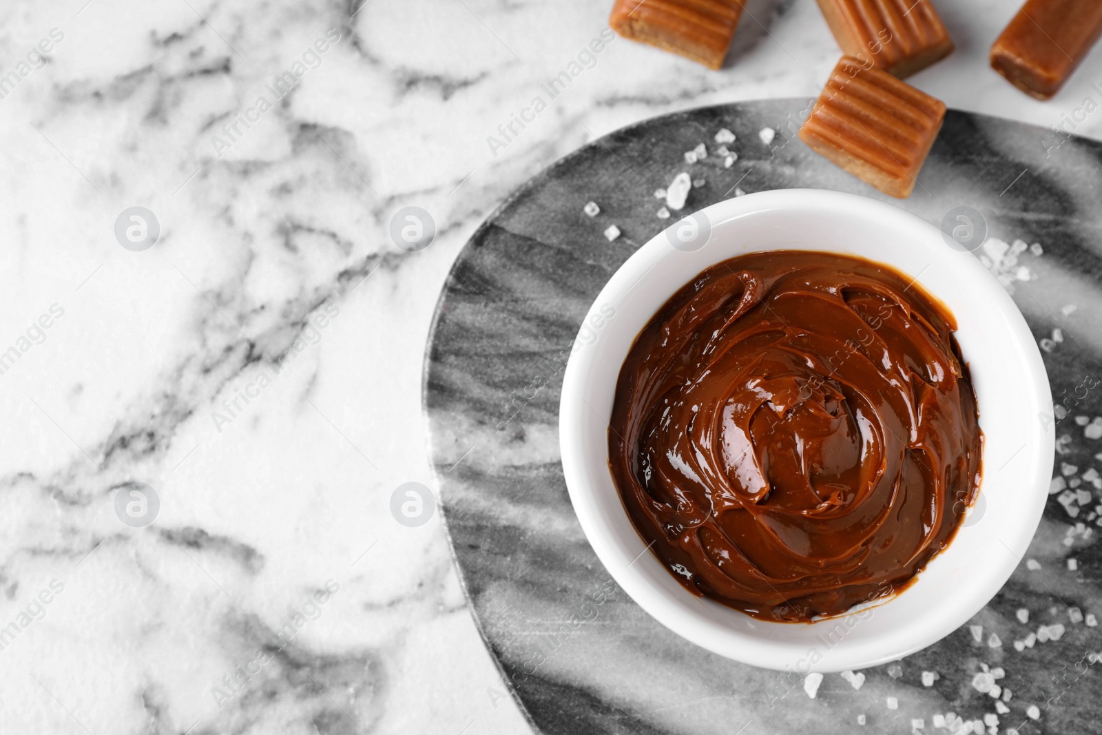 Photo of Salted caramel on marble table, flat lay. Space for text