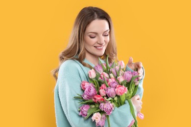 Photo of Happy young woman with bouquet of beautiful tulips on yellow background