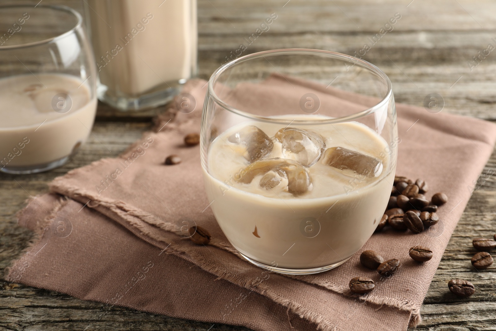 Photo of Coffee cream liqueur in glasses and beans on wooden table, closeup