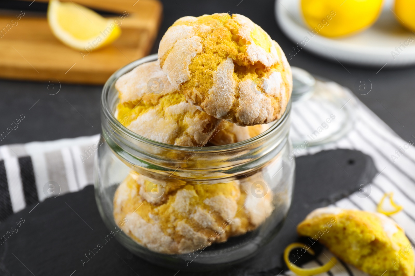 Photo of Delicious lemon cookies in glass jar on table, closeup