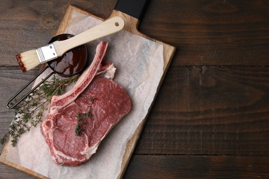 Photo of Raw meat, thyme and marinade on wooden table, top view. Space for text