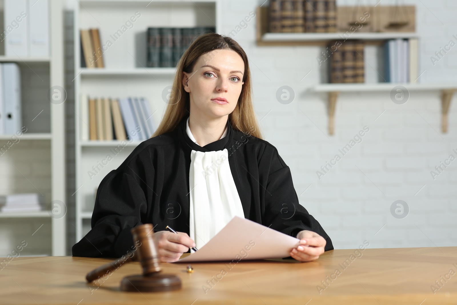 Photo of Judge working with document at table indoors. Space for text