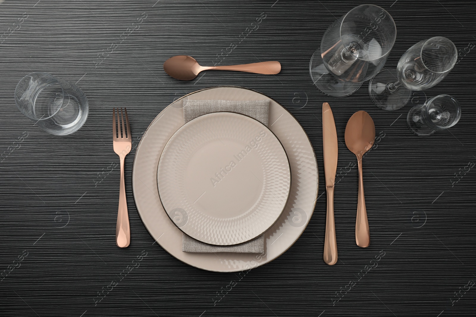 Photo of Stylish setting with cutlery, glasses and plates on black wooden table, flat lay