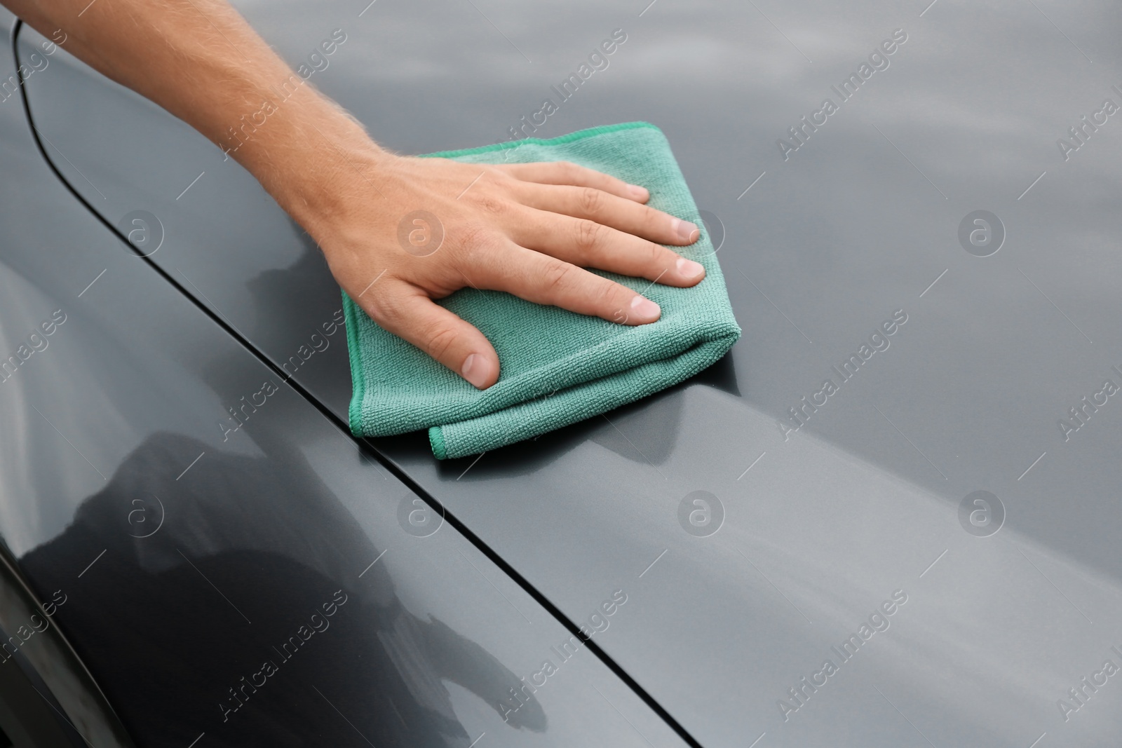 Photo of Man washing car hood with rag, closeup
