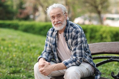 Photo of Portrait of happy grandpa with glasses on bench in park