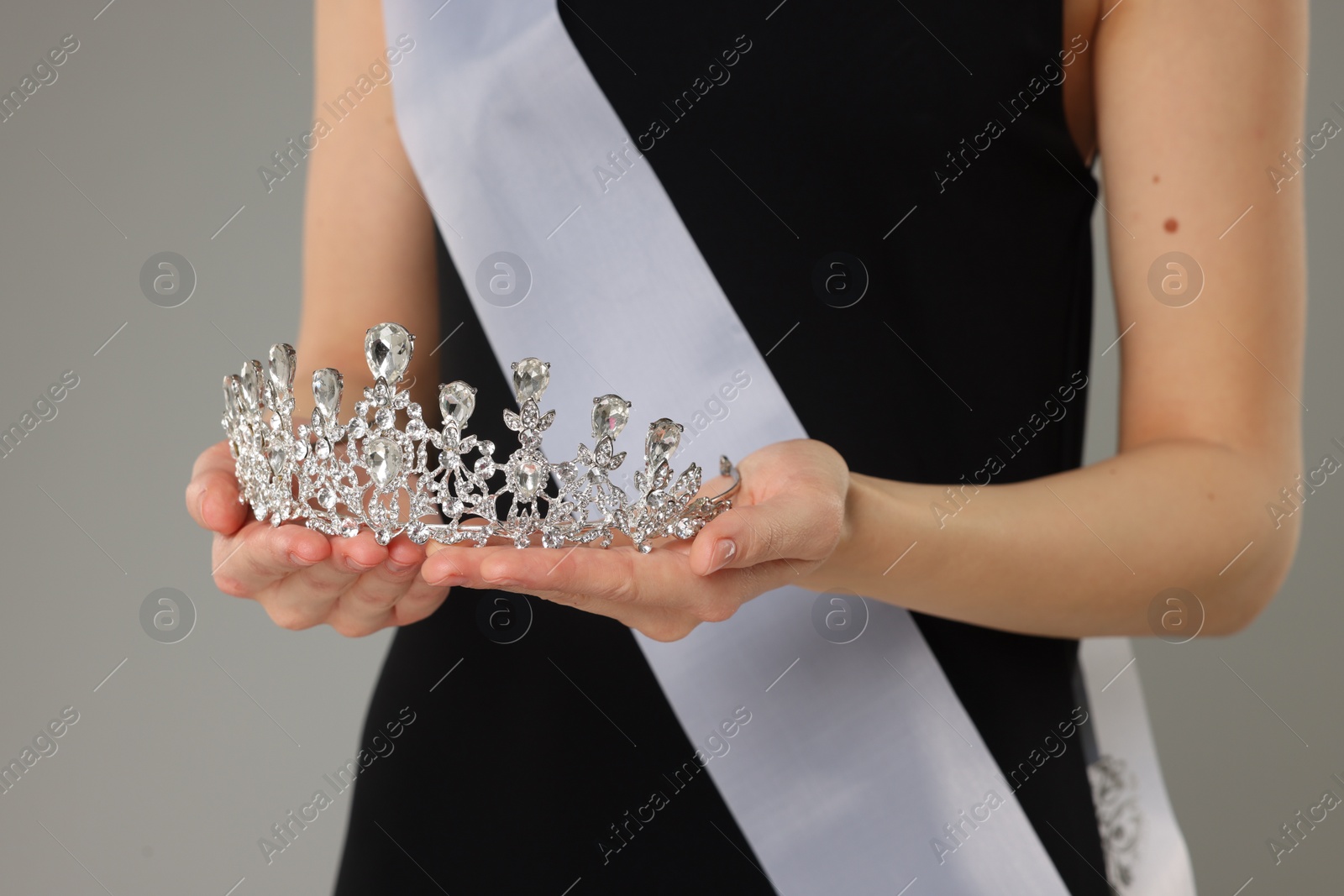 Photo of Woman in dress holding tiara on light grey background, closeup