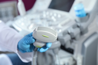 Sonographer holding ultrasound machine probe in clinic, closeup with space for text