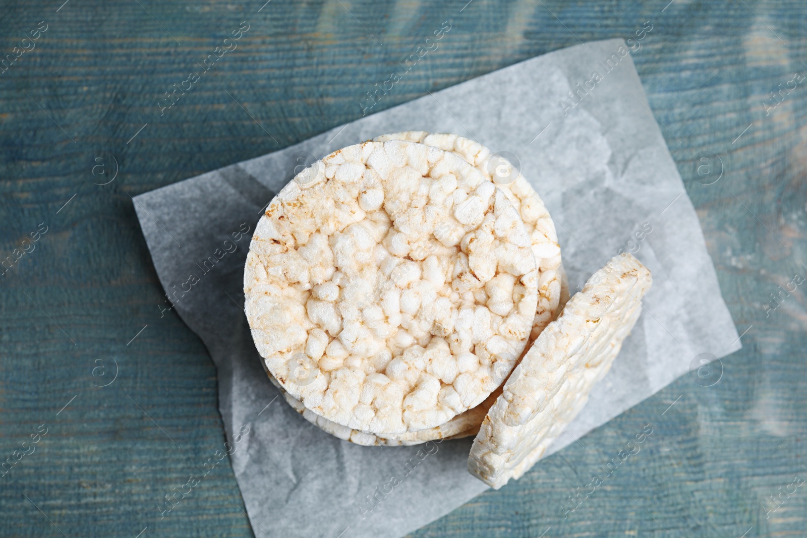 Photo of Stack of crunchy rice cakes on light blue wooden table, top view