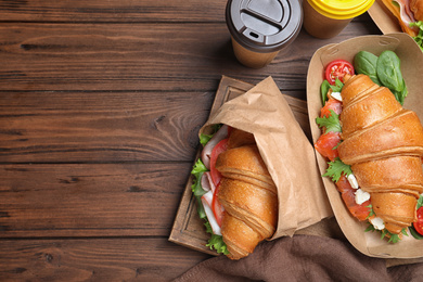 Tasty croissant sandwiches on wooden table, flat lay. Space for text