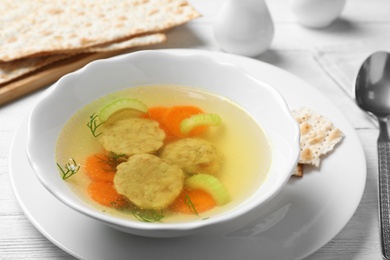 Photo of Bowl of Jewish matzoh balls soup on white wooden table