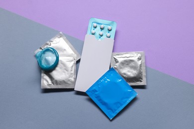 Condoms and birth control pills on color background, flat lay. Choosing method of contraception
