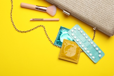 Flat lay composition with birth control pills and condoms on yellow background. Safe sex concept