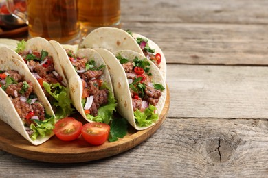 Delicious tacos with meat and vegetables on wooden table, closeup. Space for text