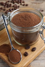 Photo of Glass jar of instant coffee and spoon on wooden table, closeup