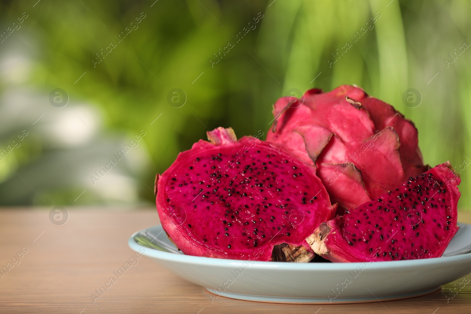 Photo of Delicious cut and whole dragon fruits (pitahaya) on wooden table. Space for text