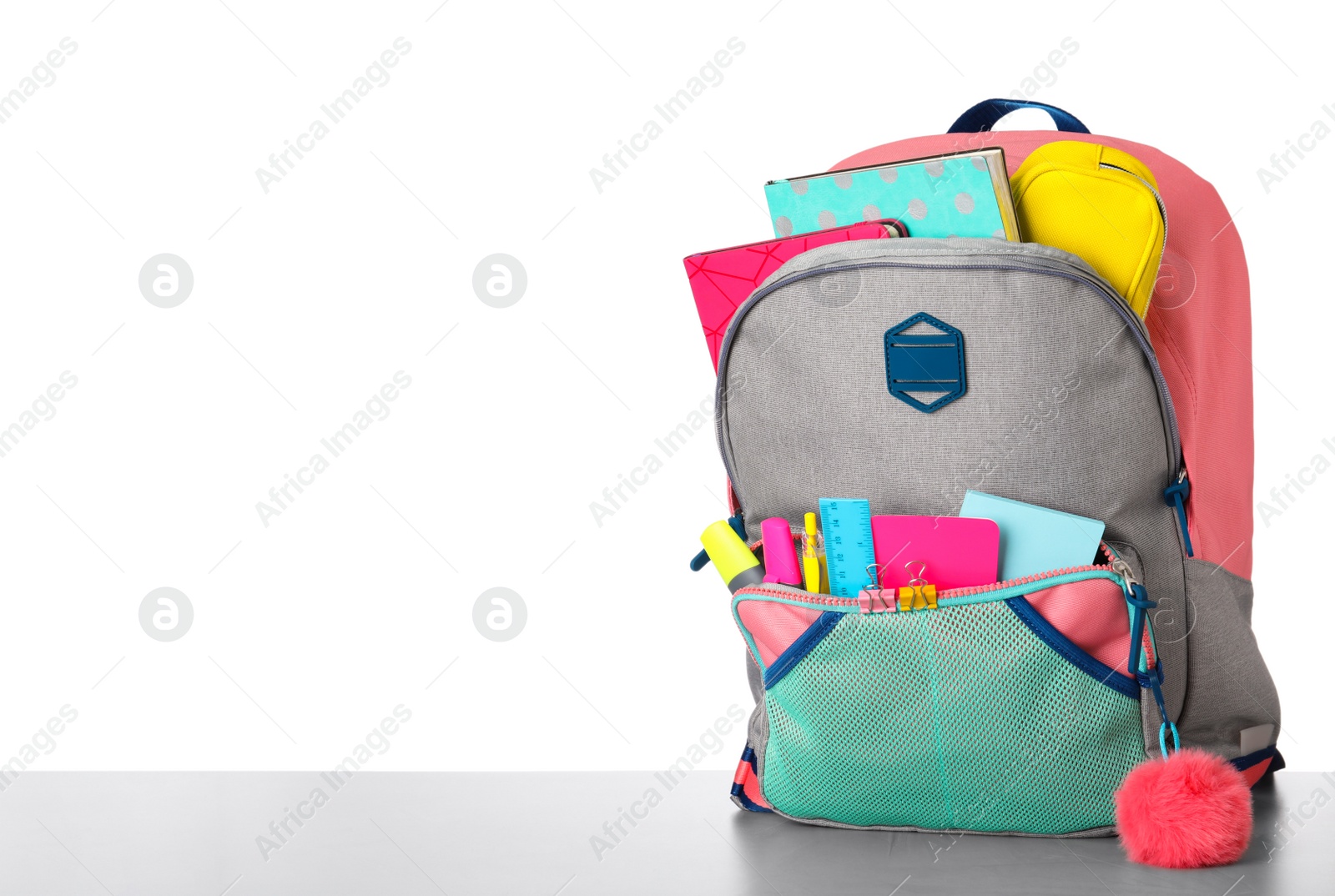 Photo of Bright backpack with school stationery on grey stone table against white background