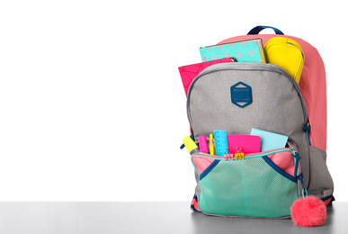 Photo of Bright backpack with school stationery on grey stone table against white background