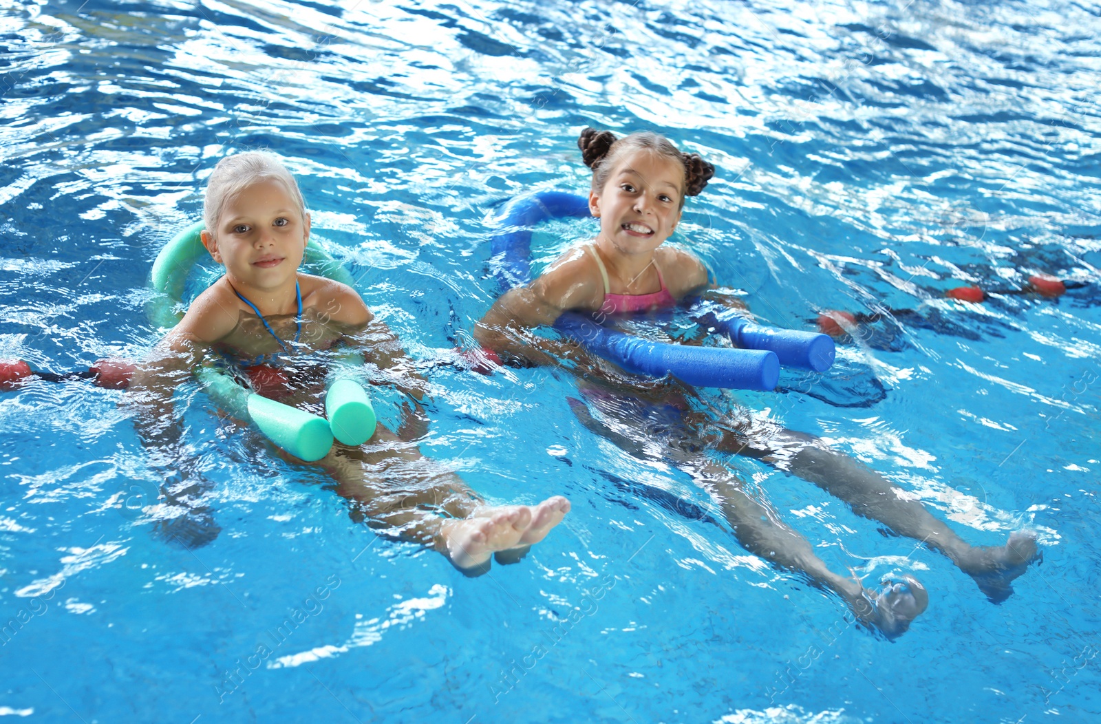 Photo of Little girls with swimming noodles in indoor pool