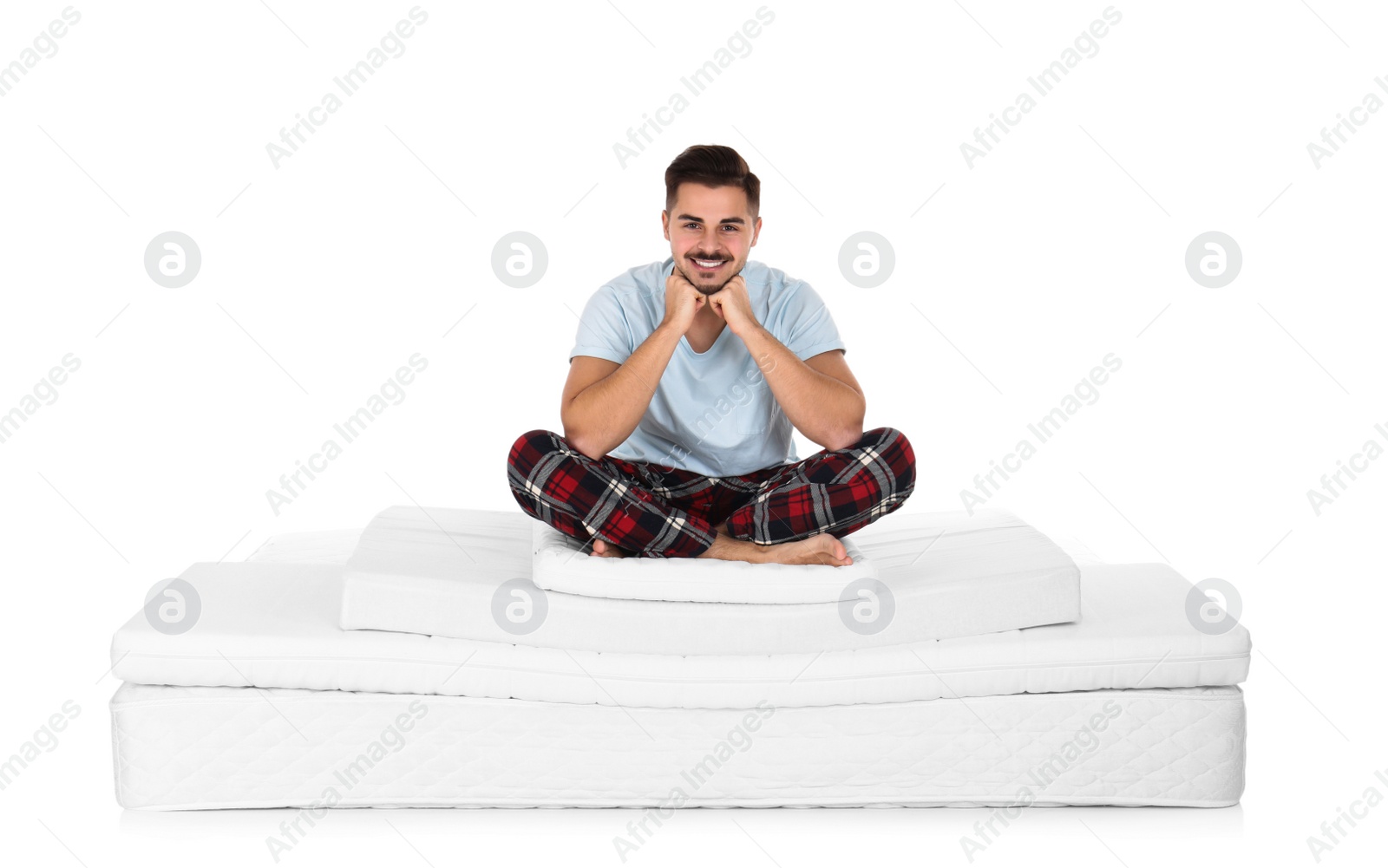 Photo of Young man sitting on mattress pile against white background