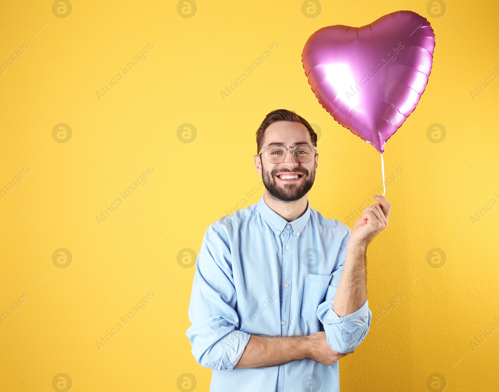 Photo of Portrait of young man with heart shaped balloon on color background. Space for text