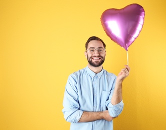 Photo of Portrait of young man with heart shaped balloon on color background. Space for text