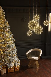 Photo of Beautiful decorated Christmas tree, chair and festive decor indoors. Interior design