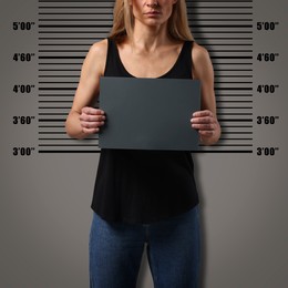 Image of Criminal mugshot. Arrested woman with blank card against height chart, closeup