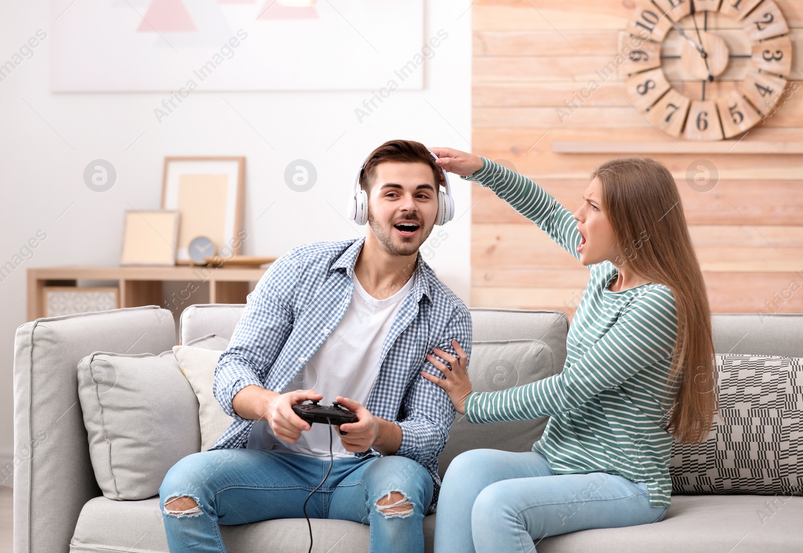 Photo of Young woman trying to draw attention of man playing video games at home
