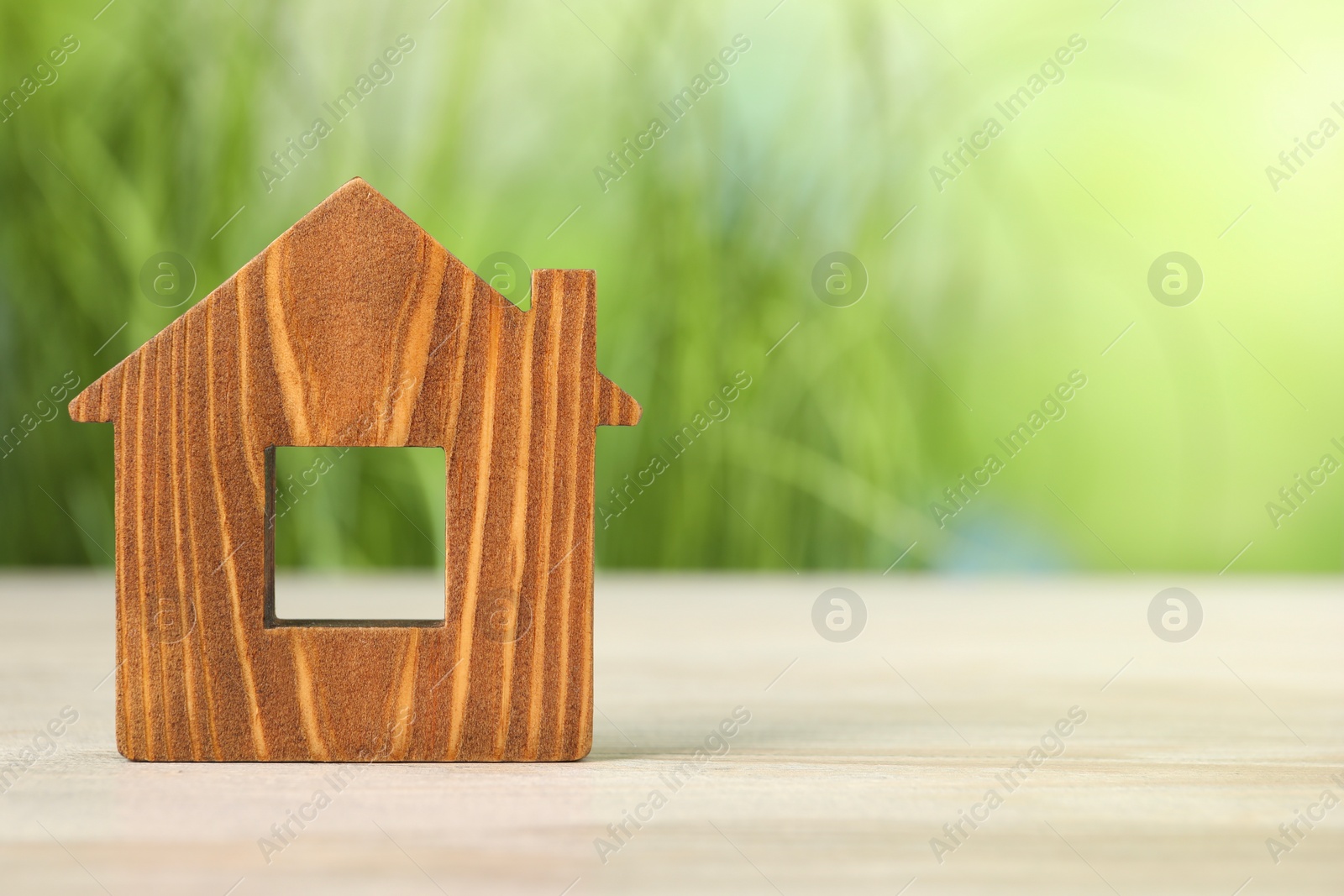 Photo of Mortgage concept. House model on white wooden table against blurred green background, space for text